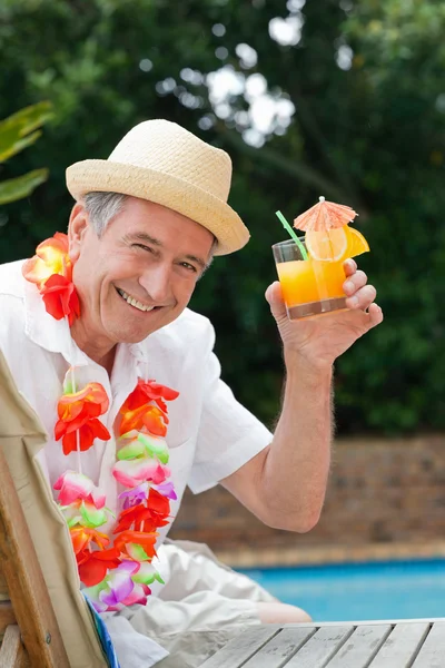 stock image Mature man drinking a cocktail beside the swimming pool