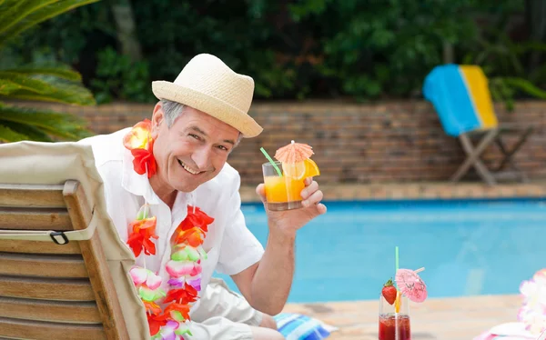 Зрелый мужчина пьет коктейль у бассейна — стоковое фото