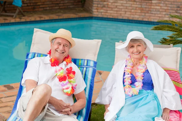 Coppia anziana sdraiata accanto alla piscina — Foto Stock