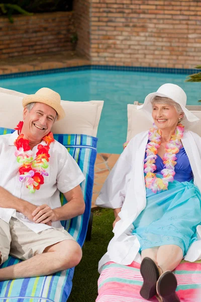 スイミング プールの横に横たわっている年配のカップル — ストック写真
