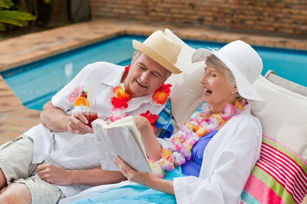 Volwassen vrouw lezen van een boek terwijl haar man een lul drinkt — Stockfoto