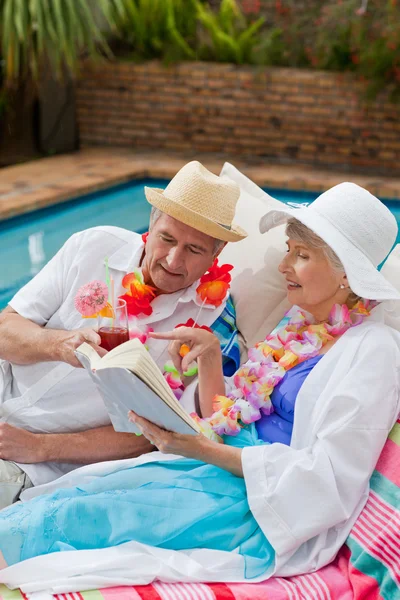 Reife Frau liest ein Buch, während ihr Mann einen Schwanz trinkt — Stockfoto