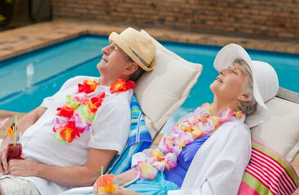 Retired couple sleeping beside the swimming pool — Stock Photo, Image