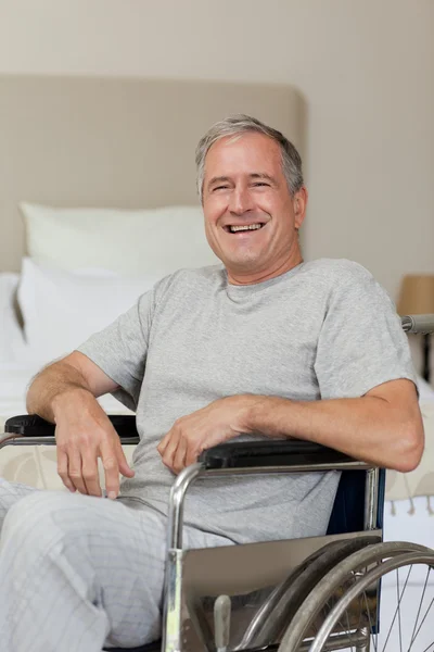 Homem senior sorridente em sua cadeira de rodas em casa — Fotografia de Stock