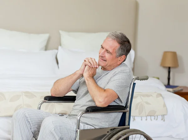 Lachende senior man in zijn rolstoel thuis — Stockfoto