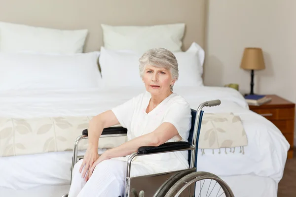 Concentrato donna anziana nella sua sedia a rotelle a casa — Foto Stock