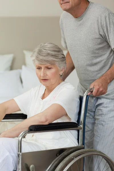 Pensionerad kvinna i hennes rullstol med maken — Stockfoto