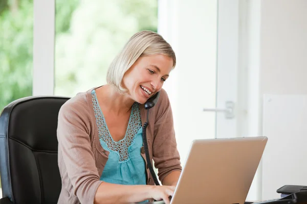 Žena pracující v počítači, zatímco ona je telefonování — Stock fotografie