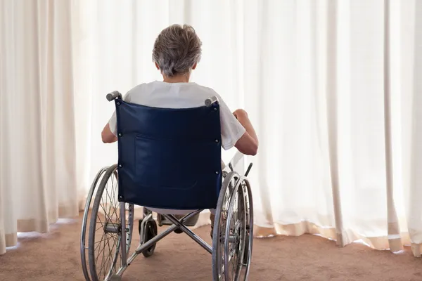 Starsza kobieta w jej wózek inwalidzki z ją z powrotem do aparatu w ho — Zdjęcie stockowe