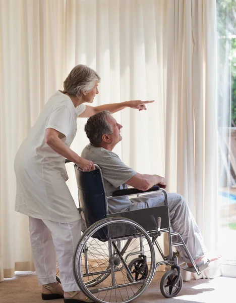 Pensionerat par tittar ut genom fönstret — Stockfoto
