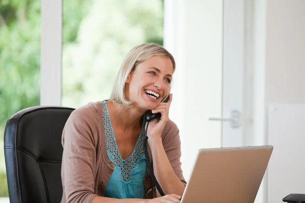 Mujer trabajando en su computadora mientras ella está llamando — Foto de Stock