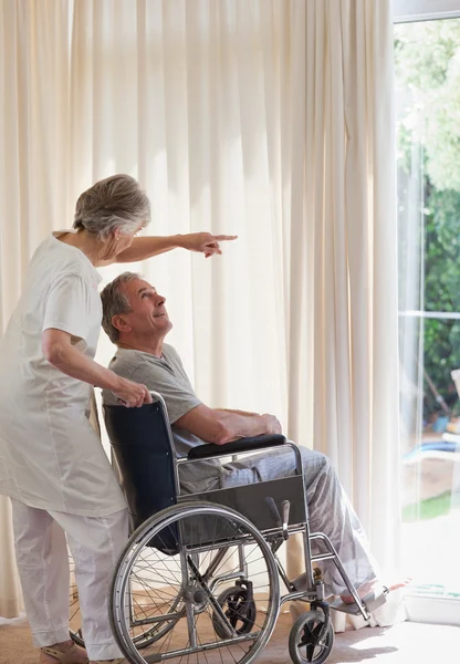Retired couple looking out the window — Stock Photo, Image