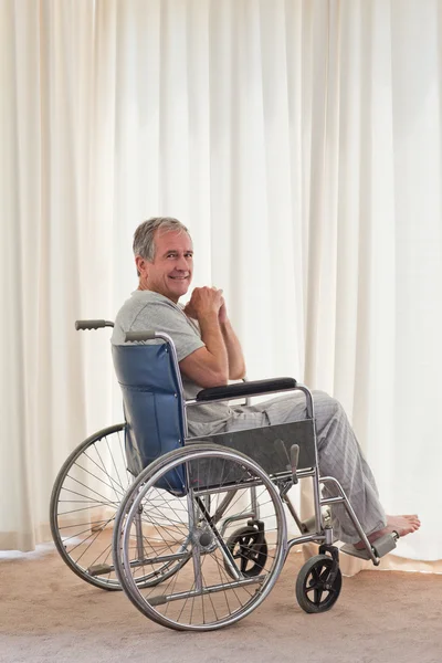 Homem sorridente em sua cadeira de rodas em casa — Fotografia de Stock