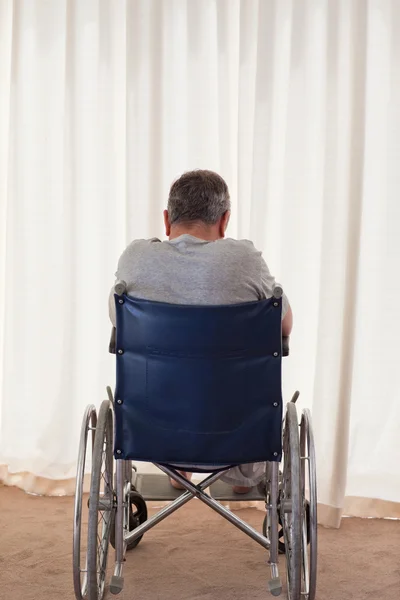 Homem maduro em sua cadeira de rodas com as costas para a câmera — Fotografia de Stock
