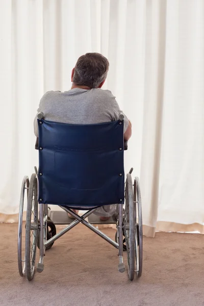 Kypsä mies pyörätuolissa selkä kameraan päin — kuvapankkivalokuva
