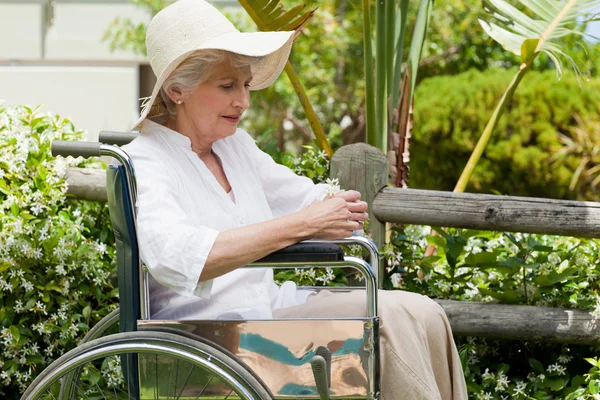 Mulher madura em sua cadeira de rodas no jardim — Fotografia de Stock
