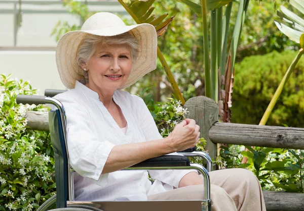 Moden kvinde i sin kørestol i haven - Stock-foto