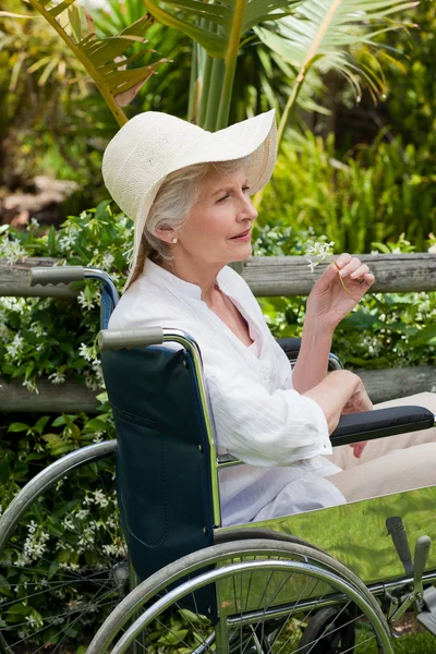 Mulher madura em sua cadeira de rodas no jardim — Fotografia de Stock