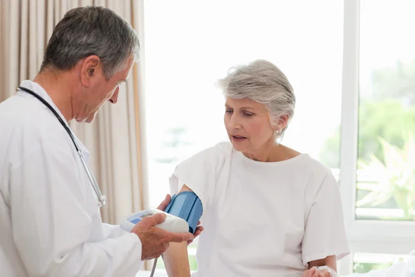 Mature doctor taking the blood pressure of his patient — Stock Photo, Image