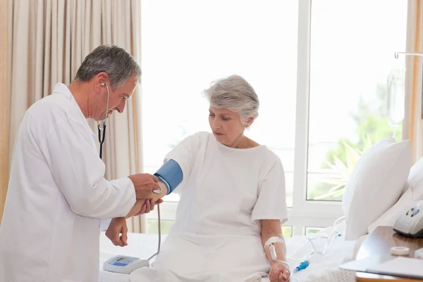 Starsze lekarz biorąc ciśnienia krwi pacjenta — Zdjęcie stockowe