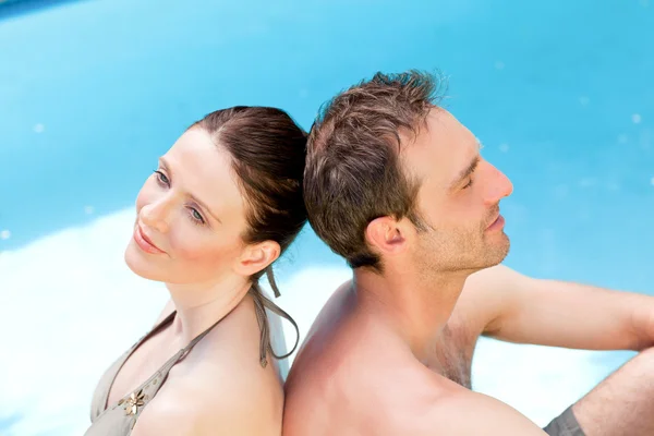 Casal sentado ao lado da piscina de costas para trás — Fotografia de Stock