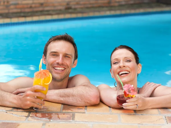 Mooi paar cocktails drinken in het zwembad — Stockfoto