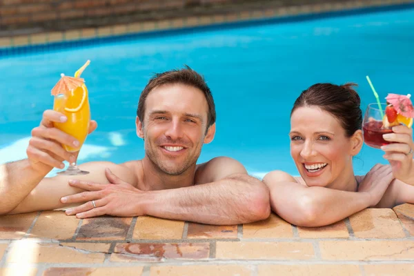 Hermosa pareja bebiendo cócteles en la piscina — Foto de Stock