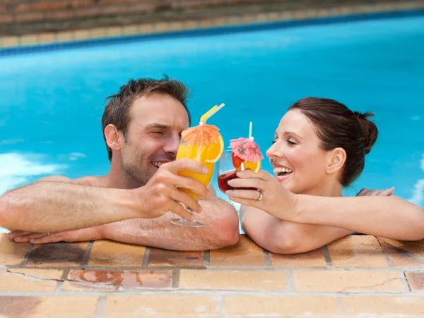 Hermosa pareja bebiendo cócteles en la piscina —  Fotos de Stock
