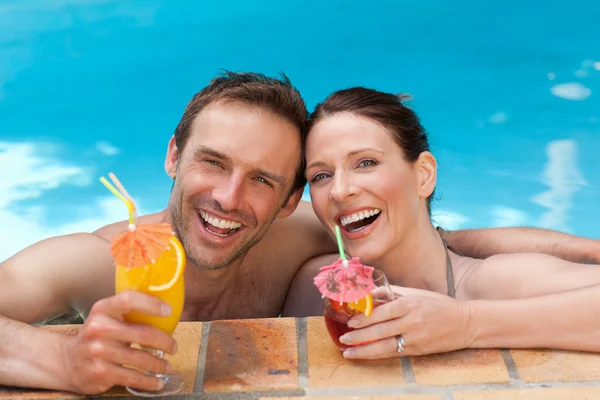 美丽的夫妇喝鸡尾酒在游泳池 — 图库照片