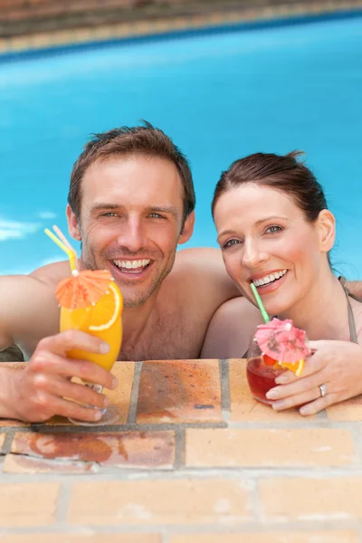 Belo casal bebendo coquetéis na piscina — Fotografia de Stock