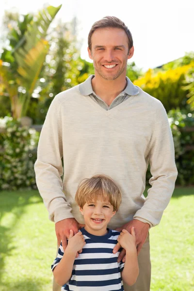 Otec a jeho syn se dívají do kamery na zahradě — Stock fotografie