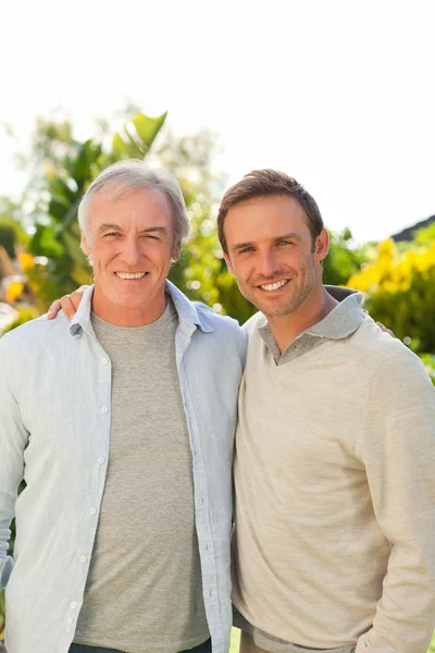 Vader en zijn zoon kijken naar de camera in de tuin — Stockfoto
