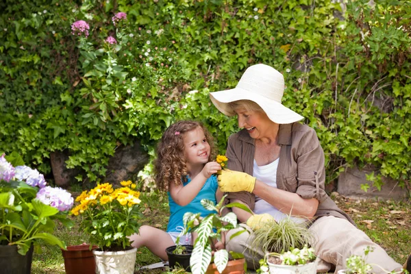 Happy Grandmother with her granddaughter working in the garden — Stock Photo, Image