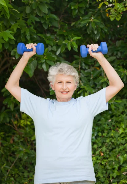 Mature woman doing her exercises in the garden — Stock Photo, Image
