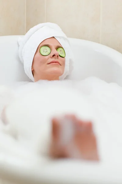 Avslappnad kvinna tar ett bad med en handduk på huvudet — Stockfoto