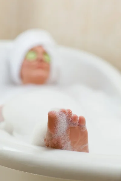 Mulher relaxada tomando um banho com uma toalha na cabeça — Fotografia de Stock