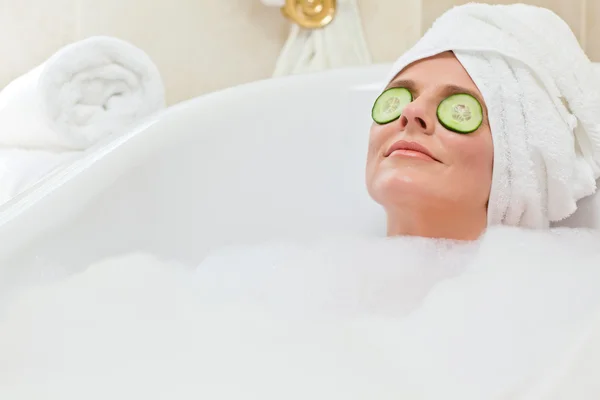 Femme détendue prenant un bain avec une serviette sur la tête — Photo