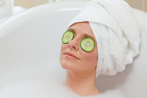 Расслабленная женщина принимает ванну с полотенцем на голове — стоковое фото