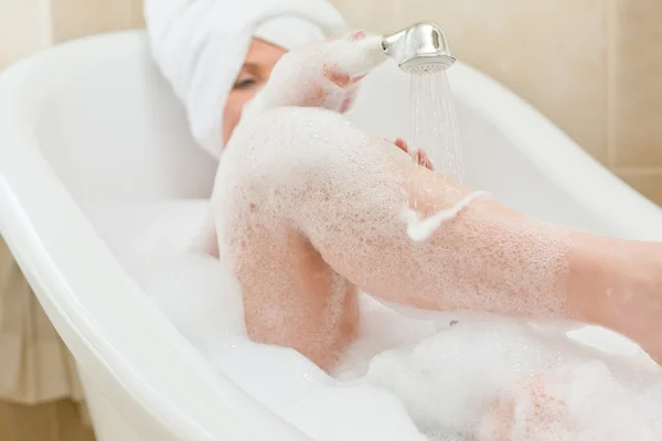Leende kvinna tar ett bad med en handduk på huvudet — Stockfoto
