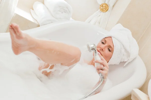 Улыбающаяся женщина принимает ванну с полотенцем на голове — стоковое фото