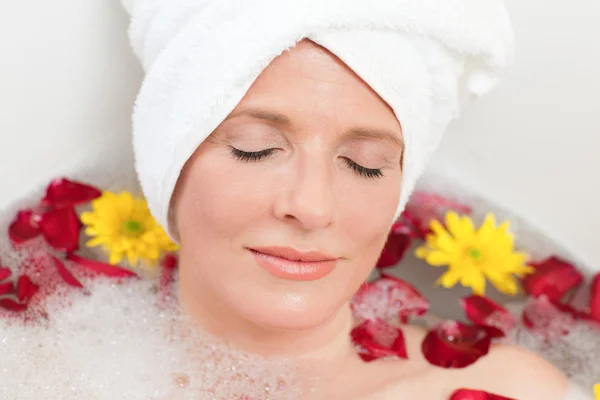 Entspannte Frau nimmt ein entspannendes Bad mit einem Handtuch auf dem Kopf — Stockfoto