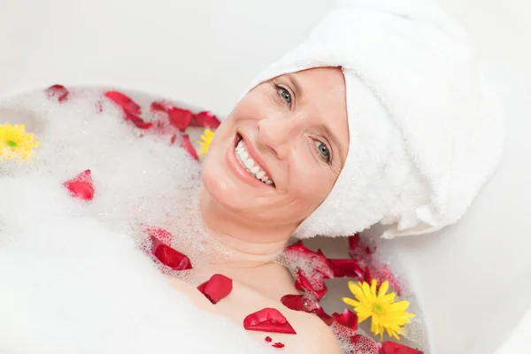 Расслабленная женщина принимает расслабляющую ванну с полотенцем на голове — стоковое фото