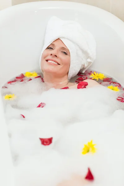 Расслабленная женщина принимает расслабляющую ванну с полотенцем на голове — стоковое фото
