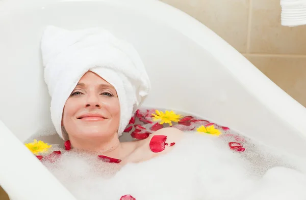 Entspannte Frau nimmt ein entspannendes Bad mit einem Handtuch auf dem Kopf — Stockfoto