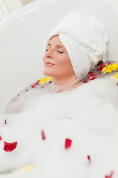 Pretty woman taking a relaxing bath with a towel on her head — Stock Photo, Image