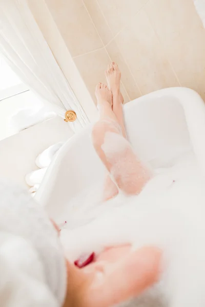 Красивая женщина принимает расслабляющую ванну с полотенцем на голове — стоковое фото