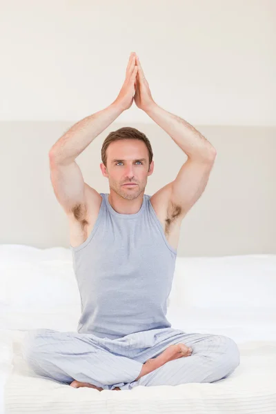 Чоловік практикує йогу на своєму ліжку — стокове фото