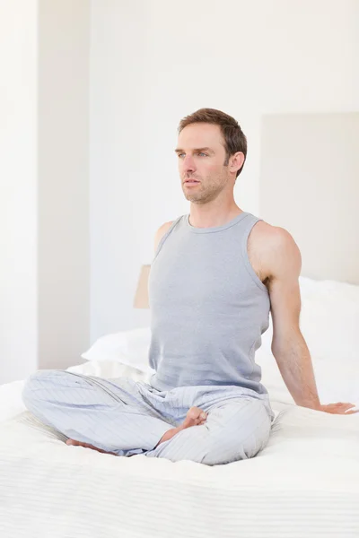 Мужчина практикующий йогу на своей кровати — стоковое фото