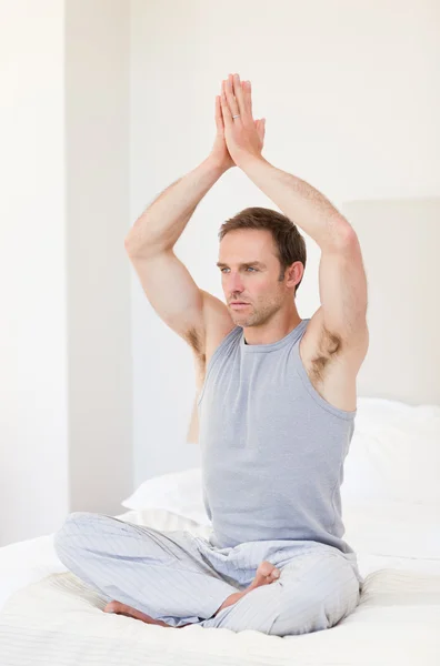 Man practicing yoga on his bed — Stock Photo, Image