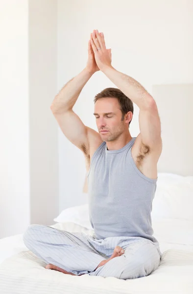 Mann praktiziert Yoga auf seinem Bett — Stockfoto